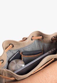 Canvas and leather bag interior with striped lining holding a laptop, wallet, metal water bottle, and smartphone in organized pockets.