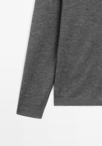 Maglione grigio con una texture liscia, maniche lunghe e orlo a coste. Design semplice senza motivi o dettagli visibili.