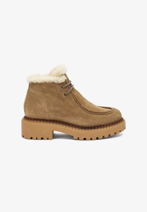Stivali alla caviglia in suede marrone con un morbido colletto di pelliccia crema, punta rotonda e suola in gomma beige spessa e texturizzata con un motivo a righe.
