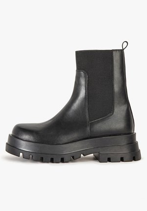 Stivali alla caviglia neri in pelle liscia e tessuto elastico. Suola in gomma spessa con battistrada profondo. Presenta una linguetta sul retro.