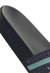 Sandale slide noire texturée avec logo Adidas trefoil en relief et une bande turquoise sur la bride supérieure texturée.