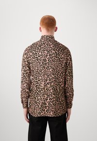 Langermige shirt in een roze stof met een zwart en groene luipaardprint, met een kraag en knoopmanchetten, van de achterkant getoond.