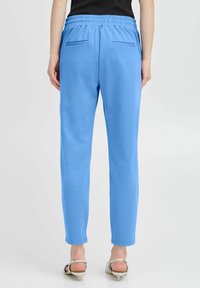 Light blue athletic pants made from soft fabric. Features an elastic waistband and two back pockets. Tapered leg design.