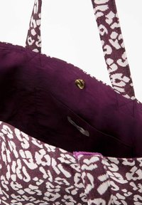  Paarse en witte gestreepte schoudertas, met een stoffen textuur, twee hengsels en een magnetische drukknoopsluiting aan de binnenkant, voorzien van een binnenzak.