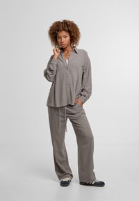 Gray button-up shirt with long sleeves, paired with matching loose pants. Both made of soft fabric, featuring a relaxed fit and drawstring waist.