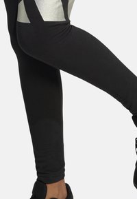 Leggings negros con un patrón geométrico plateado en el muslo, hechos de un material suave y elástico para mayor comodidad y flexibilidad.
