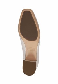 Semelle d'une chaussure pour femme en caoutchouc beige clair avec une surface texturée. Présente un talon léger et le nom de la marque imprimé, "Caprice".