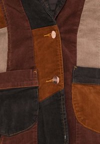Cordoijacket met een patchworkontwerp in bruin, zwart en grijs. Voorzien van twee zakken, metalen knopen en zichtbare stiksels.