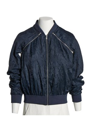Blouson bomber bleu marine foncé avec fermeture éclair frontale, poignets et ceinture côtelés, et fermetures éclair diagonales décoratives près des épaules.