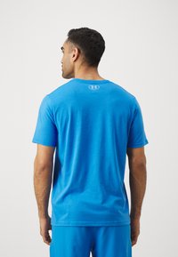 Blue short-sleeve t-shirt featuring a crew neck and a subtle logo at the back neckline, made from a soft, textured fabric.