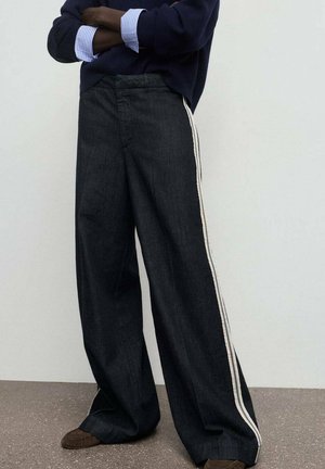 Pantalones de mezclilla de pierna ancha en azul oscuro con un acabado texturizado, que presentan franjas laterales blancas en contraste y un diseño de cintura alta.