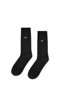 Czarne bawełniane skarpetki z prążkowanymi ściągaczami i wzmocnionymi palcami; na boku znajduje się małe białe logo. Gładka tekstura, klasyczny design.