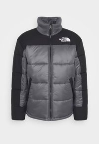 Dynejakke i grå og sort med høj krave, lynlås og vandret quiltet design. Logo på øverste venstre side.