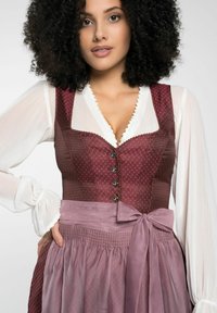 Robe traditionnelle avec un corsage bordeaux profond à pois, des boutons décoratifs, et une jupe lilas agrémentée d'un nœud ; manches blanches.
