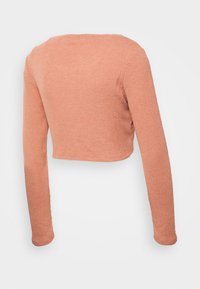 Kortärmad topp med långa ärmar i ljus persikofärgad ribbad mjukvara. Har en bred halsringning och figurnära ärmar, med en strukturerad yta och rena kanter.