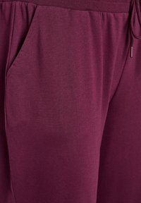 Burgunderfarbene Jogginghosen mit elastischem Bund, seitlichen Taschen, glatter Stoffstruktur und verstellbarem Kordelzug.