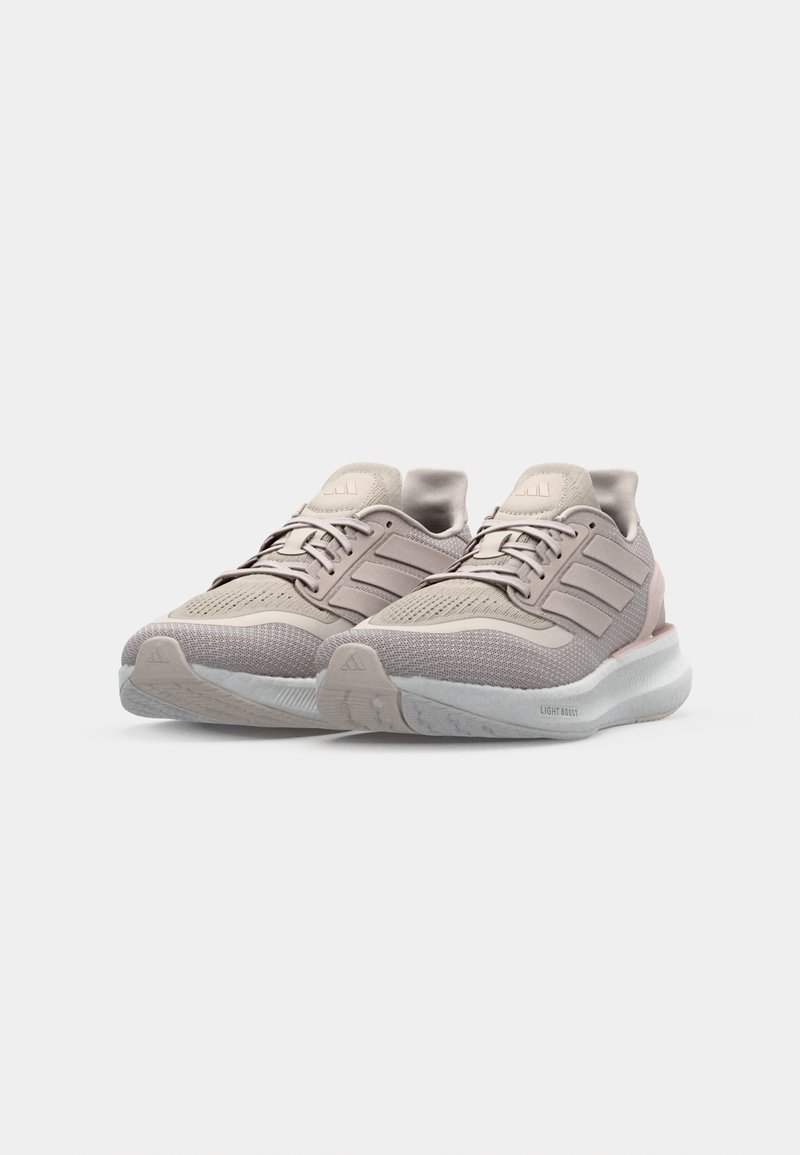 Baskets légères pour athlétisme en beige clair et rose doux. Présentent une tige en maille respirante, des lacets et une semelle blanche rembourrée avec le logo 'LIGHT BOOST'.