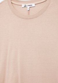 Camiseta de color rosa claro hecha de suave algodón. Presenta un escote redondo, mangas cortas y detalles de costura mínimos. Etiqueta de la marca visible.