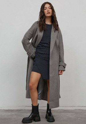 Long gray coat over a navy striped dress. Black ankle boots with chunky soles. Smooth fabric with a tailored design and relaxed fit.