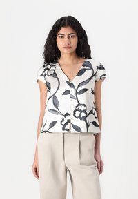 Blusa in seta crema a maniche corte e scollo a V con stampa floreale nera, dotata di bottoni lungo il davanti e una vestibilità cropped rilassata.