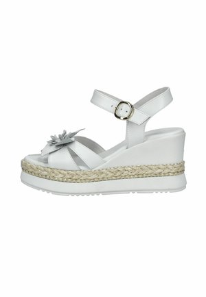 Sandale blanche compensée avec bride à la cheville, plateforme en jute tressé et ornement floral sur la lanière de l'orteil.