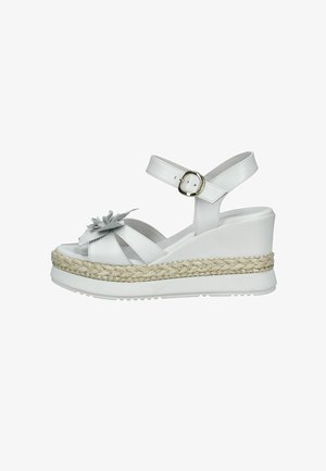 Sandale blanche compensée avec bride à la cheville, plateforme en jute tressé et ornement floral sur la lanière de l'orteil.