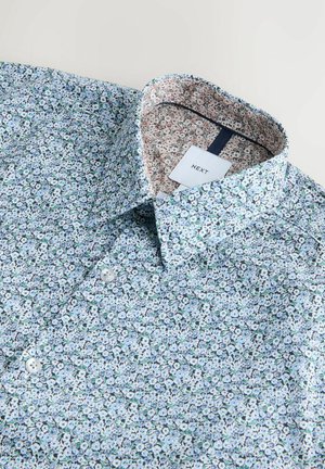 Floral patterned shirt featuring a light blue background and small white flowers. Collared design with a patterned inner lining and two buttons.