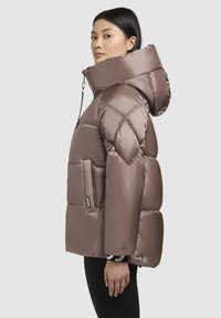 Puserjakke i blød taupe, med høj krave, kviltet design, sidelommer og en aftagelig hætte med snore.