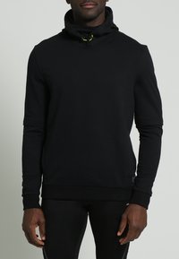 Felpa nera con collo alto, chiusura con coulisse, maniche lunghe e polsini e orlo a costine. Realizzata in tessuto liscio e di colore uniforme.