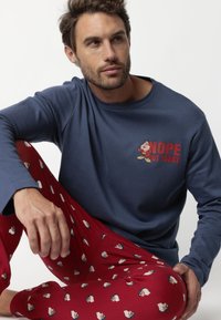 Camisa de manga larga azul marino con el texto "NOPE NOT TODAY" y gráfico de dibujos animados; pantalones de pijama rojos con un pequeño patrón repetido de personajes de dibujos animados.