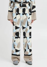 Pantalones de pierna ancha con un patrón geométrico en azul, negro, beige y blanco, con una tela texturizada y detalle de cintura en contraste.