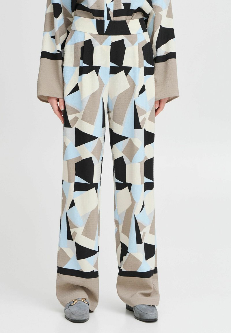 Pantalones de pierna ancha con un patrón geométrico en azul, negro, beige y blanco, con una tela texturizada y detalle de cintura en contraste.
