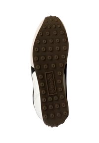 Hvid og sort sportsko sål med tekstureret gummi, der har cirkulære nubbe for traction og et logoaftryk på hælområdet.