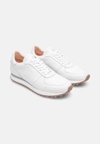 Sneakers bianchi in pelle con una texture liscia, design con lacci e suola in gomma marrone chiaro, con un logo discreto sulla linguetta.