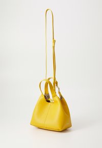 Borsa a mano gialla in pelle con finitura testurizzata, forma arrotondata, due manici corti e una tracolla lunga regolabile.