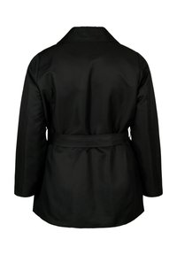 Svart kappa med skärp i midjan, långa ärmar och mjuk textur. Har en klassisk krage och generös skärning baktill.