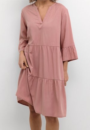 Rosa Baumwollkleid mit V-Ausschnitt, dreiviertel Ärmeln und einem gestuften Rüschensaum. Der Stoff hat eine glatte Textur und einen lockeren Schnitt.