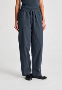 Pantaloni di un blu scuro, morbidi e comodi, con cintura elastica e cordoncino di regolazione. Realizzati in un materiale morbido, presentano un design a gamba dritta e senza motivi visibili.