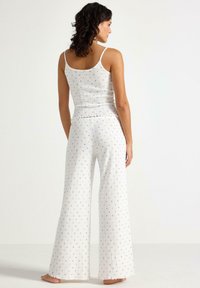 Vitt ribbad pyjamasset med blå blommönster. Ärmstopp och byxor med vida ben. Mjuk tyg med en texturerad yta.