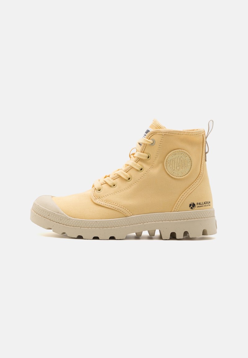 Bottes basses en toile jaune avec embout en caoutchouc et semelle texturée ; présentent un logo circulaire et un design à lacets.