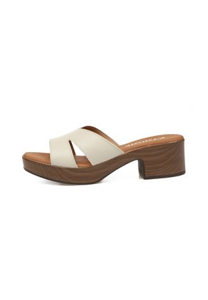 Sandalia mule blanca de piel con punta abierta, tacón bloque de madera y plantilla acolchada marrón, vista lateral.