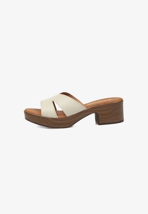 Sandalia mule blanca de piel con punta abierta, tacón bloque de madera y plantilla acolchada marrón, vista lateral.