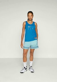 Blue tank top with "FLY" text and silver accents, paired with light blue shorts featuring a diamond pattern and black stripes. Worn with white socks and shoes.