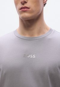 Γκρι κοντομάνικη μπλούζα από βαμβάκι, με διακριτικό λογότυπο "BOSS" στο στήθος σε αντίθετο φινίρισμα, με στρογγυλή λαιμόκοψη.