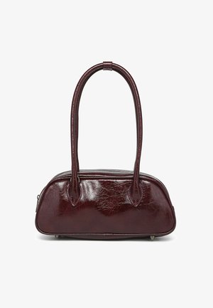 Burgundijas mākslīgās ādas rokassoma ar noapaļotu formu, divām garām rokām un tekstūrētu virsmu. Aprīkota ar aizsargājošām metāla kājām apakšā.