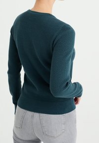 Teal textured knit sweater with a round neckline and ribbed cuffs and hem, featuring a fitted silhouette and a subtle, patterned finish.