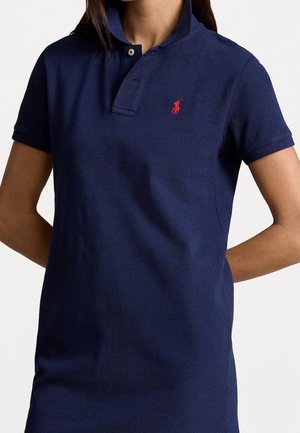 Polo bleu marine en coton avec une finition texturée, doté d'un col, de manches courtes et d'un petit logo rouge sur la poitrine.