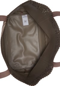 Sac fourre-tout avec une extérieure en similicuir beige, des détails découpés au laser le long du bord supérieur, et une doublure intérieure lisse de couleur beige.