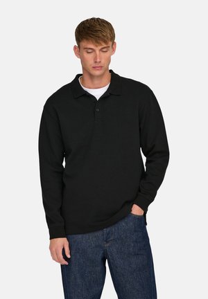 Polo negro de manga larga con cuello, tapeta de tres botones y textura suave, combinado con unos jeans de mezclilla de corte relajado.