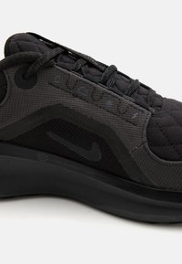 Baskets de course noires avec un tige en tissu texturé, présentant des accents renforcés, un col rembourré et un design épuré. Logo Nike sur le côté.